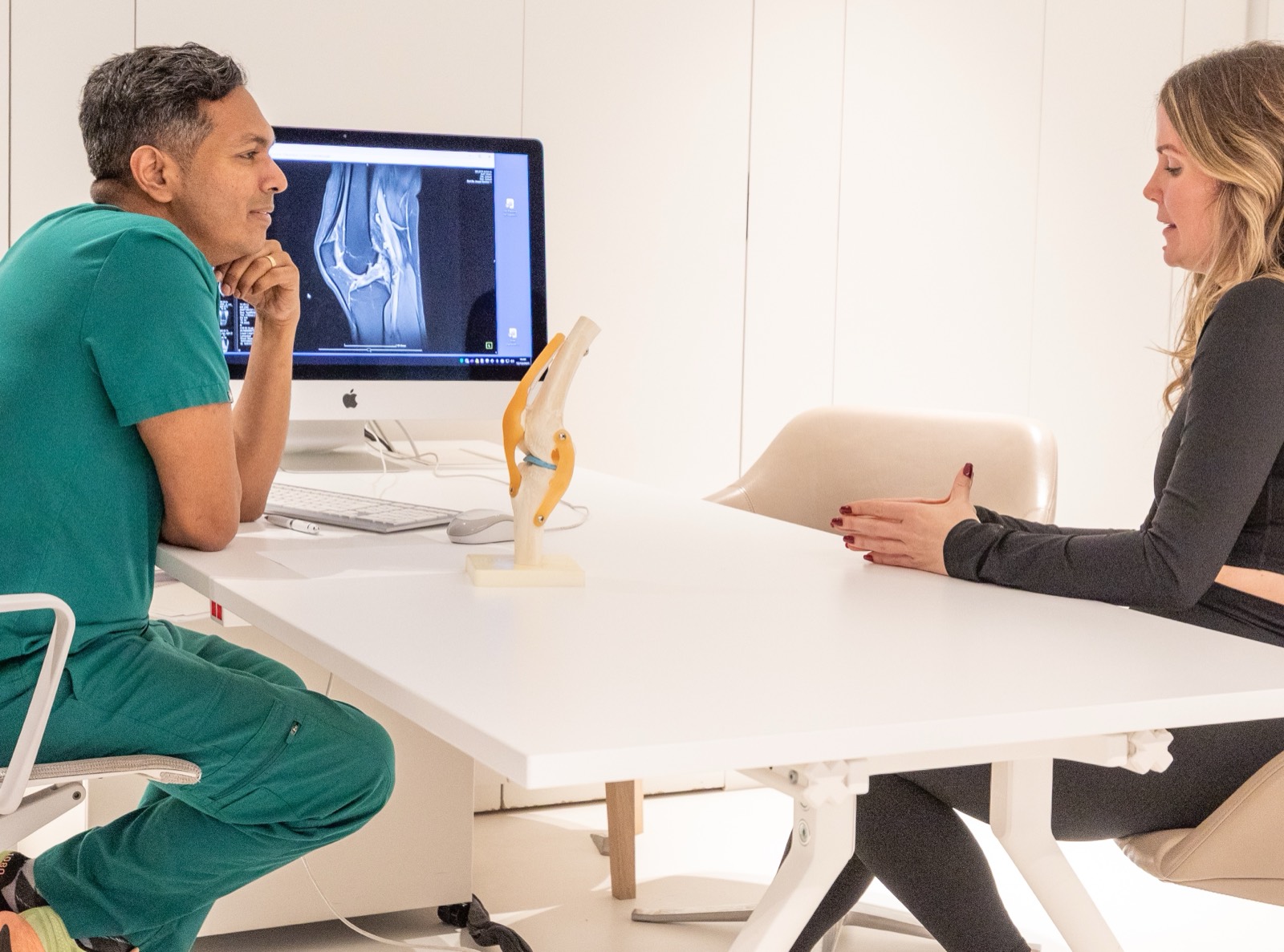 Dr Arj Imbuldeniya reviewing a patient's knee MRI during a consultation